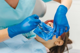 Koferdam - dentystka przeprowadzająca leczenie u pacjentki z koferdamem