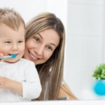 Jak dbać o zęby dziecka - mama ucząca synka myć zęby
