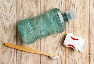 Domowe sposoby na zapalenie dziąseł - szczoteczka do zębów, nić dentystyczna i butelka z płynem do płukania jamy ustnej