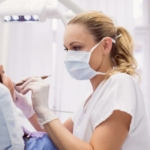 Usuwanie kamienia nazębnego - dentystka usuwająca kamień nazębny pacjentowi