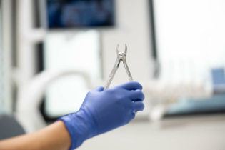 Zatrzymane ósemki - dentysta trzymający w ręce szczypce dentystyczne
