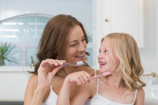 Jak zachęcić dzieci do mycia zębów - mama i córka w łazience myjące zęby