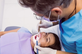 Choroby przyzębia diagnostyka - dentysta badający jamę ustną pacjentki
