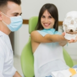 Fizjoterapeuta stomatologiczny - fizjoterapeuta stomatologiczny i pacjentka trzymająca model czaszki człowieka