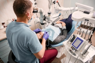 Wkład koronowo-korzeniowy - dentysta leczący pacjentkę pod mikroskopem