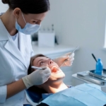 Leczenie periodontologiczne - pacjentka na fotelu stomatologicznym podczas badania jamy ustnej przez dentystkę