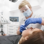 Sanacja jamy ustnej - dentystka lecząca zęby pacjentki leżącej na fotelu